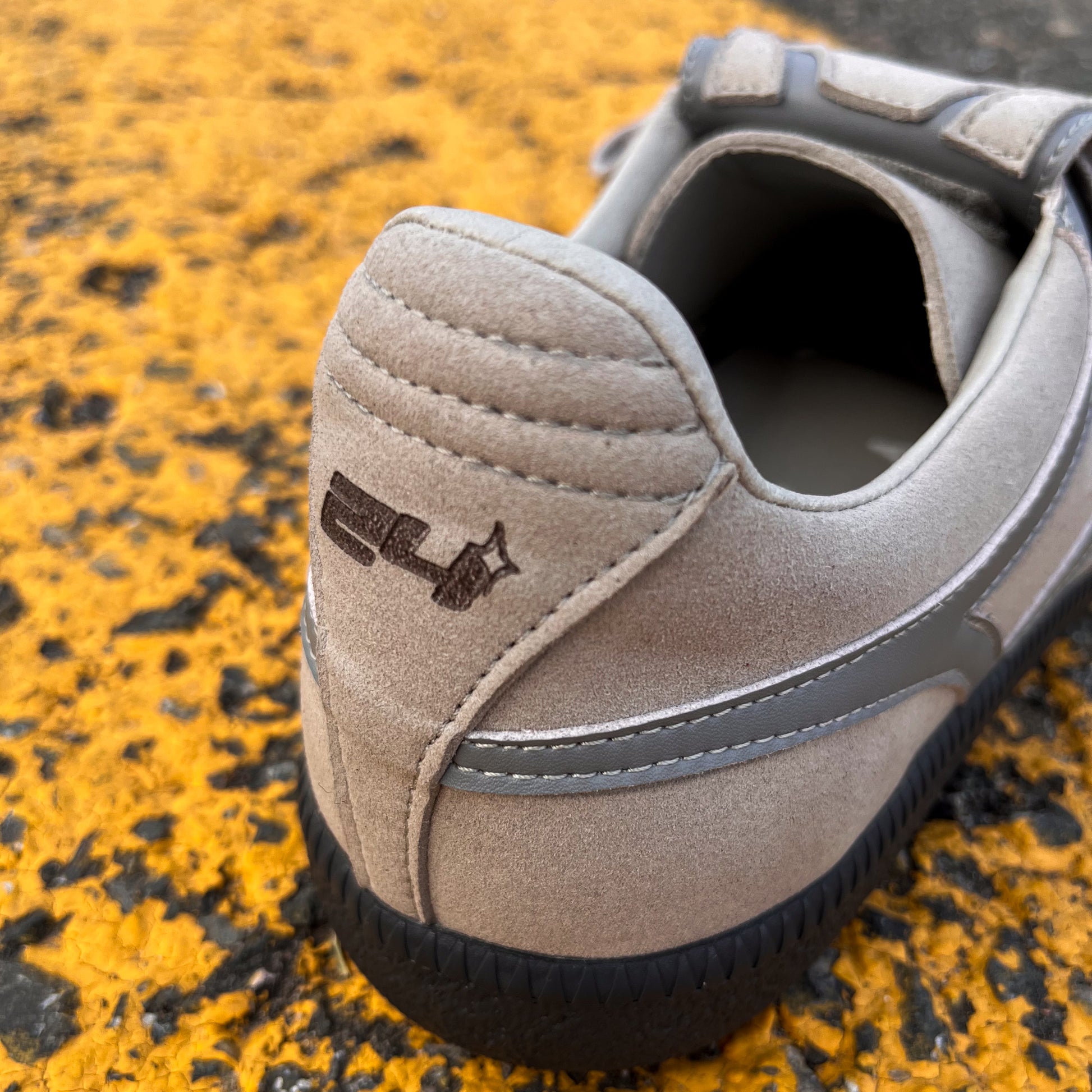 Grauer veganer Sneaker Tardelli von twentyfourdegree auf gelber Asphaltlinie