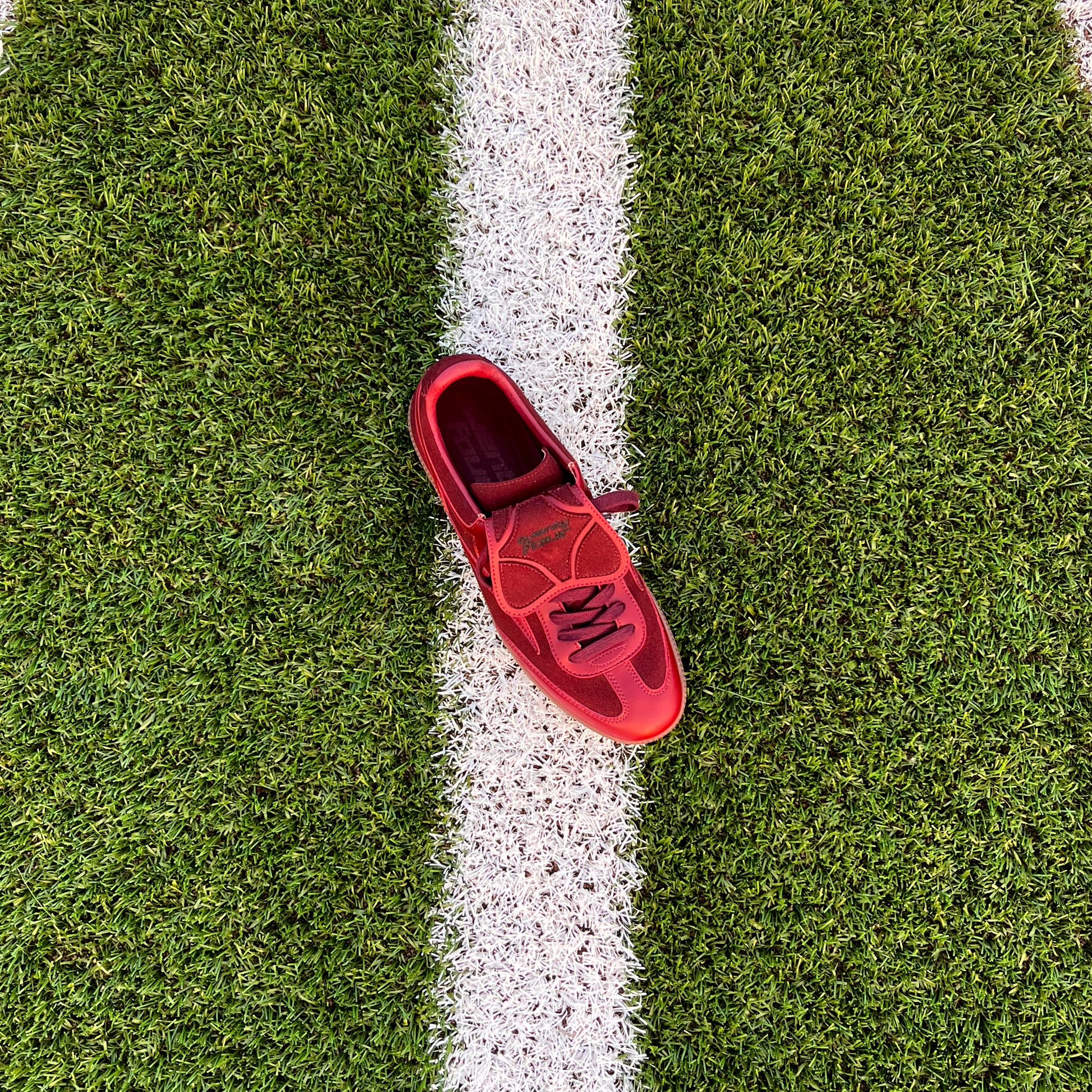 Bordeaux-roter twentyfourdegree Graziani Sneaker aus veganem Apfelleder auf weißer Linie eines Footballfeldes