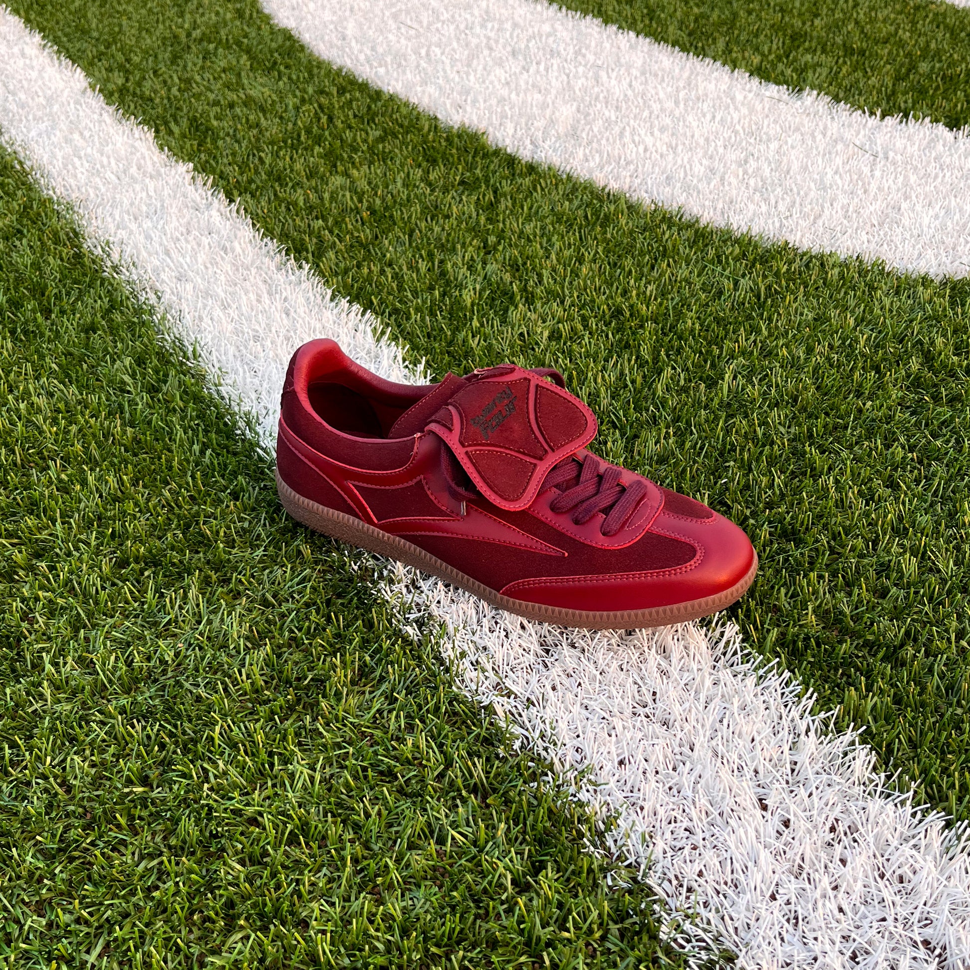 Bordeaux-roter twentyfourdegree Graziani Sneaker aus Apfelleder auf weißer Markierung eines Footballfeldes