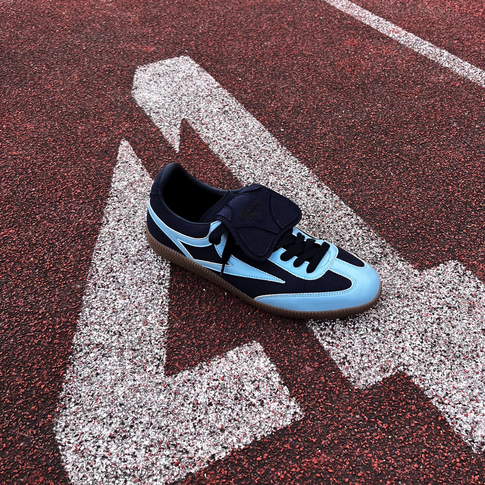 Marineblauer twentyfourdegree Sneaker aus Apfelleder, hellblaue Akzente, auf roter Laufbahn